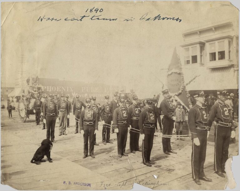 1890 photograph of an early Bellingham fire department hose company in uniform with a hose carriage on a plank street