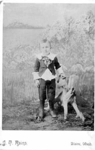 Around 1885 photograph of a young boy standing beside an enormous redcedar stump in Blaine, Washington