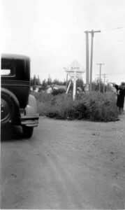 1927 photograph of a woman beside a road sign with an early automobile in Blaine, Washington