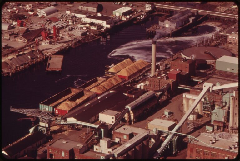 1973 color photograph of wood-chip barges beside the Georgia-Pacific pulp mill on the Bellingham waterway