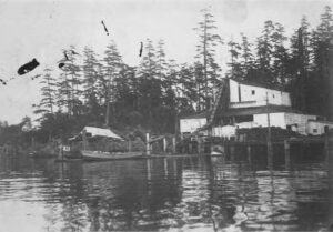 Wooden waterfront buildings and a fishing boat at a dock on Lummi Island around 1910
