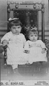 Studio portrait of two young girls in matching dresses, Lynden, around 1888