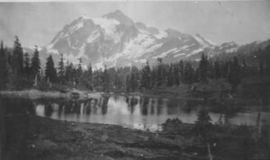 Snow-covered Mount Baker reflected in a calm lake, 1920s