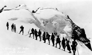 A roped party of mountaineers ascending a snowy slope on Mount Baker around 1925
