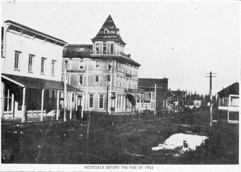 Photograph of the dirt main street of early Nooksack, Washington lined with wood-frame buildings and a hotel in the 1890s
