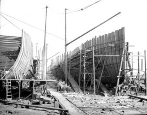 1916 photograph of two wooden ship hulls under construction at the Pacific American Fisheries shipyard