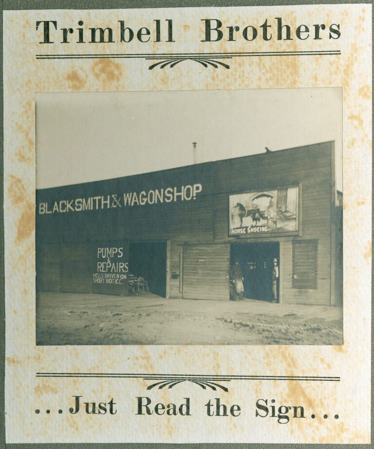 False-front Trimbell Brothers blacksmith and wagon shop in Sumas, Washington, 1891, with two men in the doorway