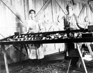 Cannery workers placing cut salmon on smoking trays in a smokehouse, 1916