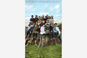 Group of schoolchildren standing on top of a giant redcedar tree stump, around 1909