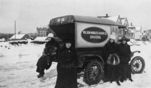 Four women standing beside an early grocery delivery truck, Whatcom County, around 1910