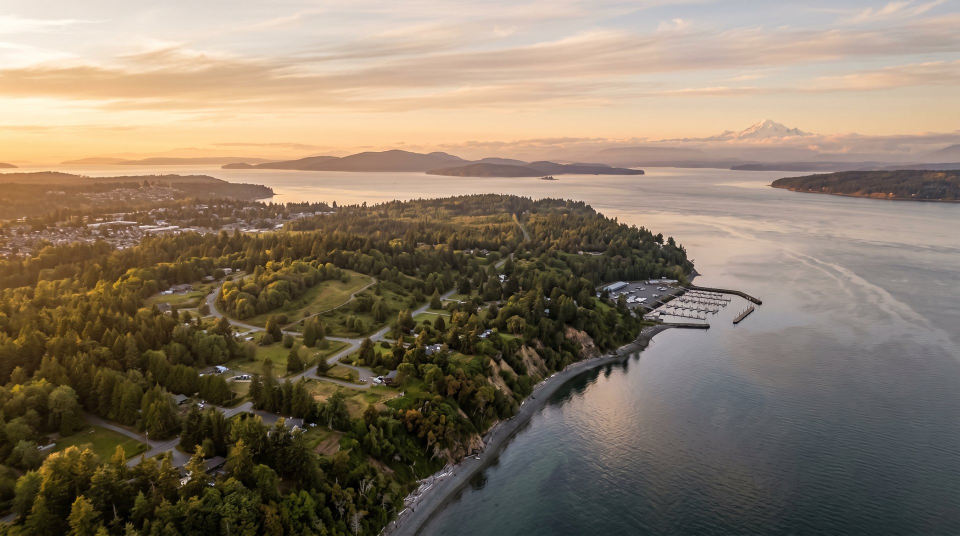 Golden-hour aerial view over Point Roberts peninsula with marina, madrona bluffs, and Mount Baker in the distance